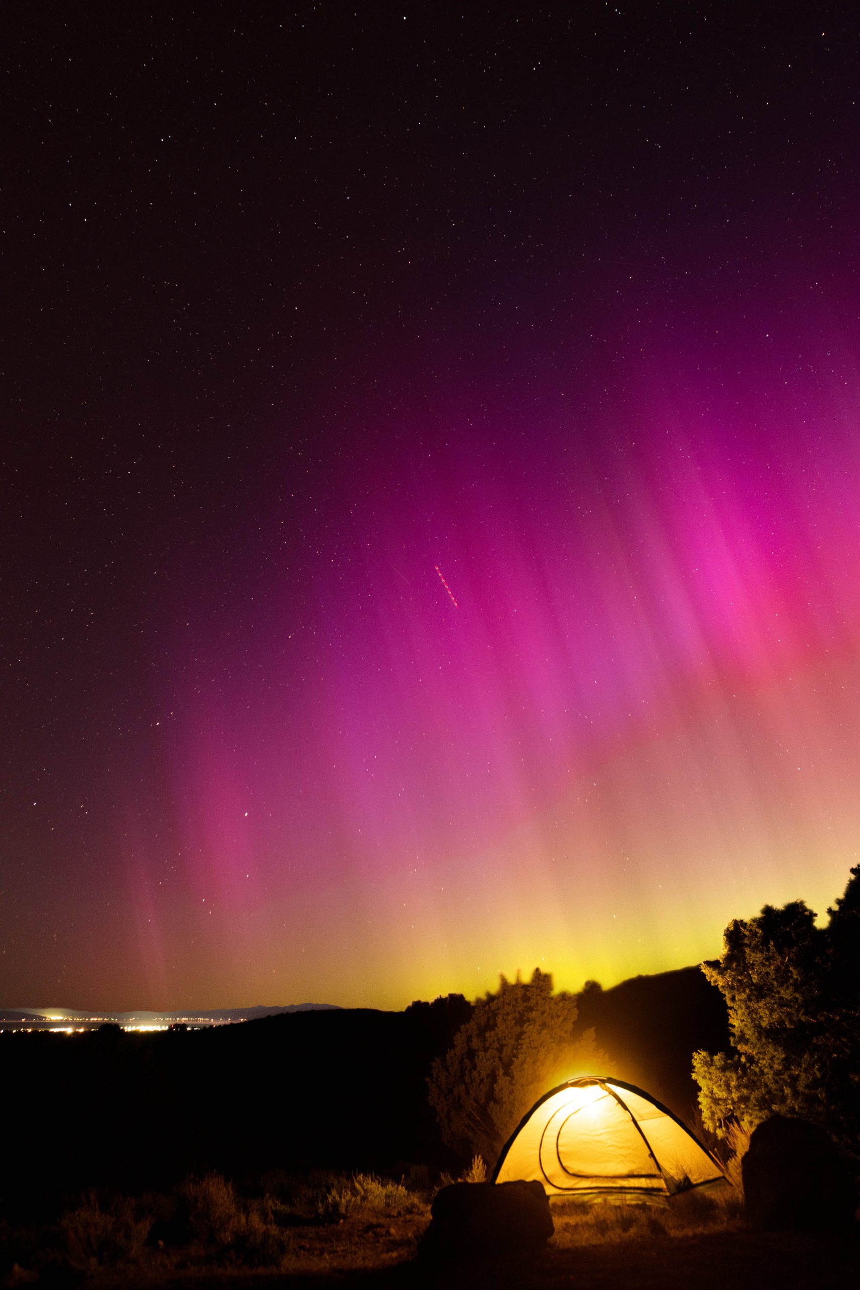 Pink aurora with yellow tent lit up at night - self-sufficiency